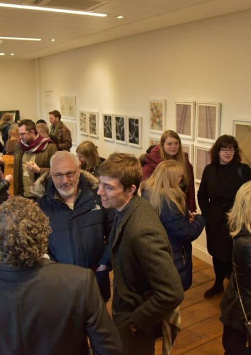 People mingling infront of displays, enjoying glasses of champagne.