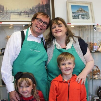 A family smiles into the camera ahead of the display shelves behind them.