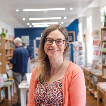 A woman smiles, posing for the camera in the book shop.