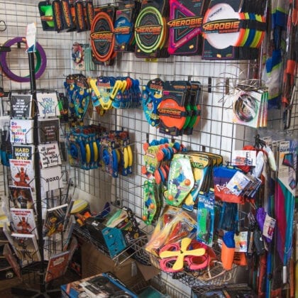 Frisbies and other throwing toys line a shop wall.