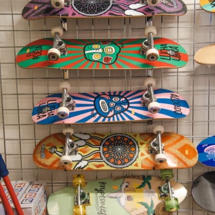Skateboards stacked vertically on a mesh metal fence inside a shop.