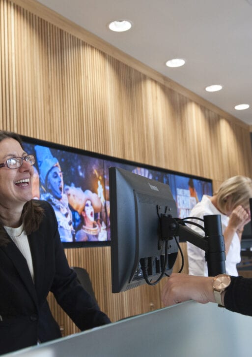 A woman laughs with the receptionist at the front desk.