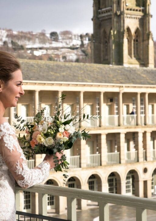 A bride looks out onto the courtyard of the piece hall, holding a bouquet.